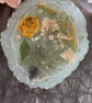 Handmade resin coaster with yellow and white dried flowers and a little of silv 