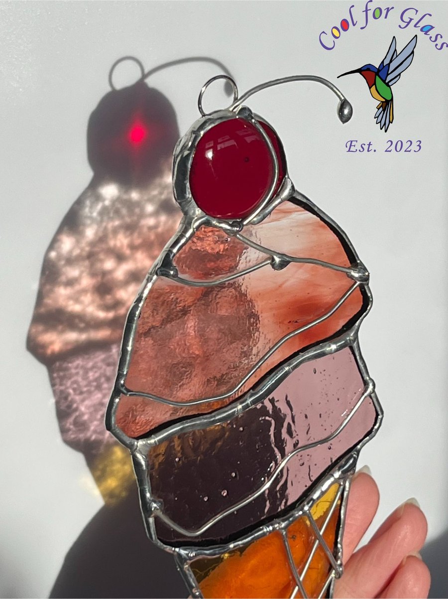 Stained glass ice-cream cone with cherry on top.