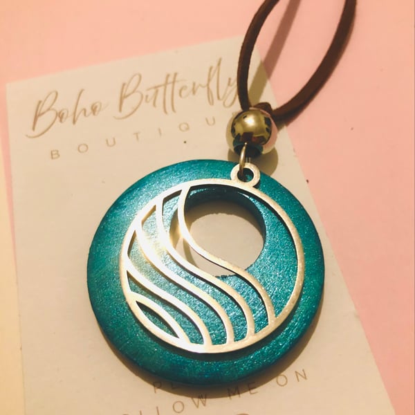 Large teal coloured wood pendant with a wave design