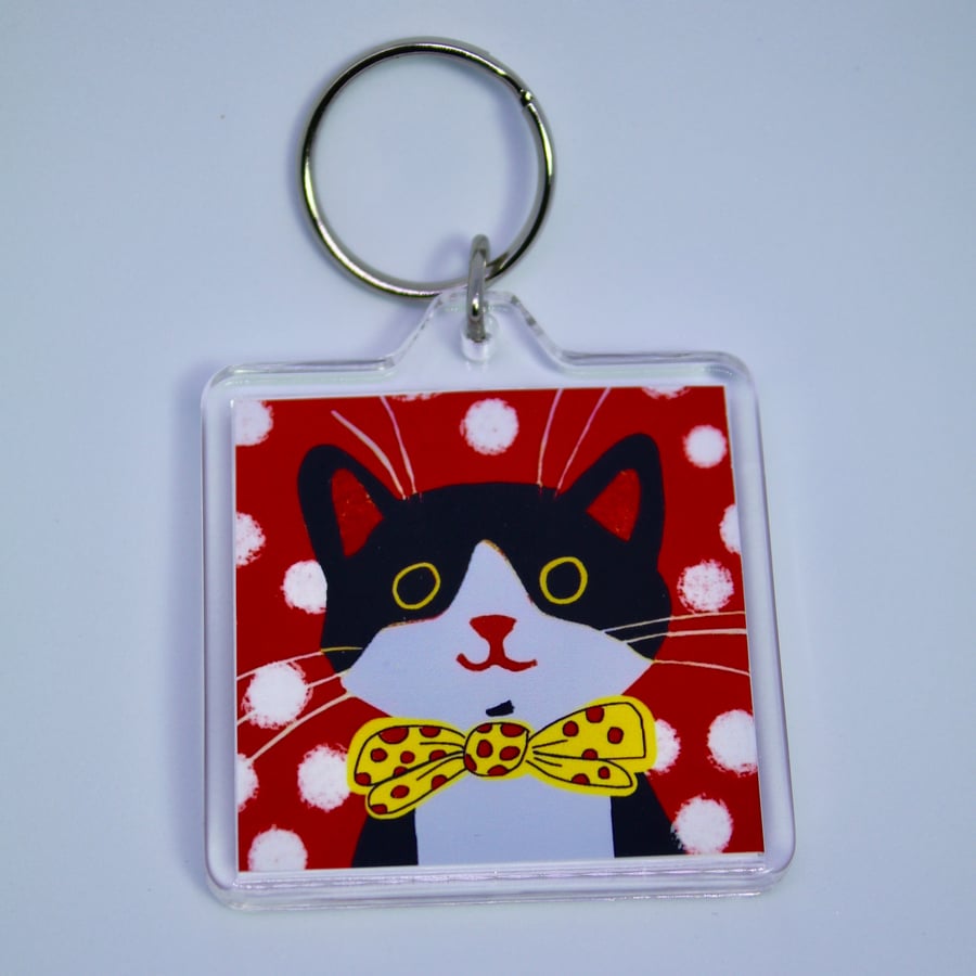 LITTLE BLACK AND WHITE HAPPY CAT KEYRING WITH RED BACKGROUND