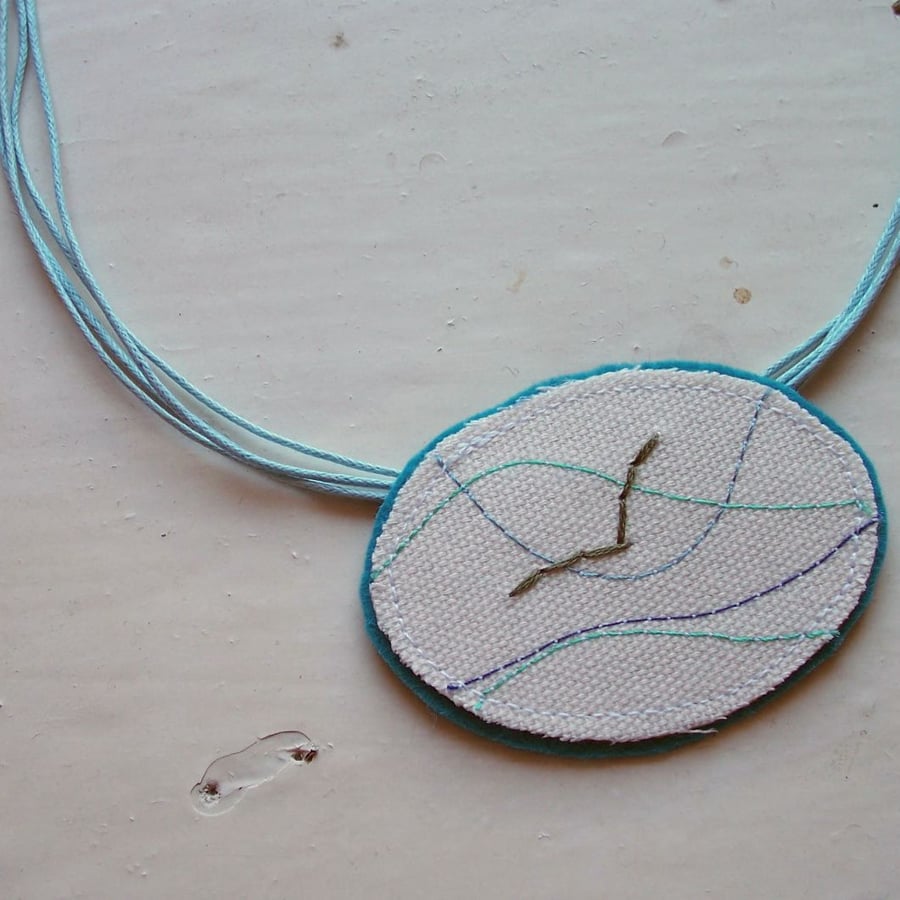 Textile necklace with embroidered seagull.