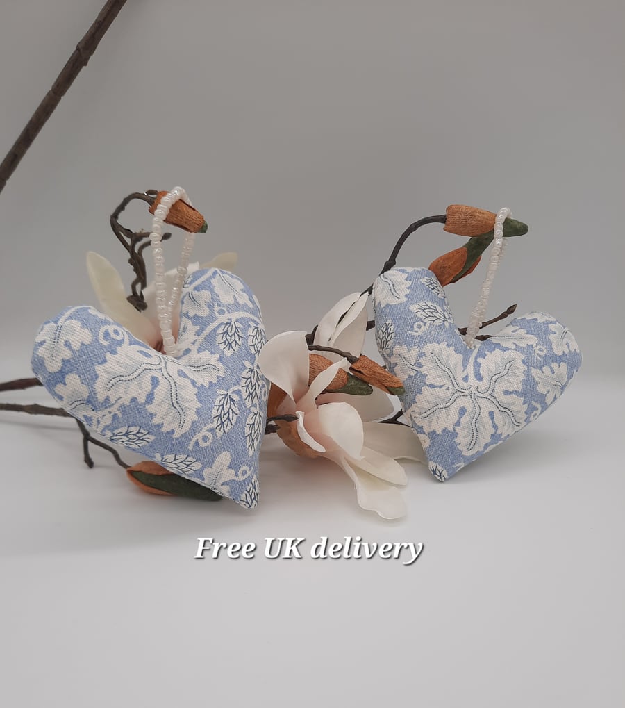 A pair of blue and white foliage fabric heart hangers with beaded hanging cord. 