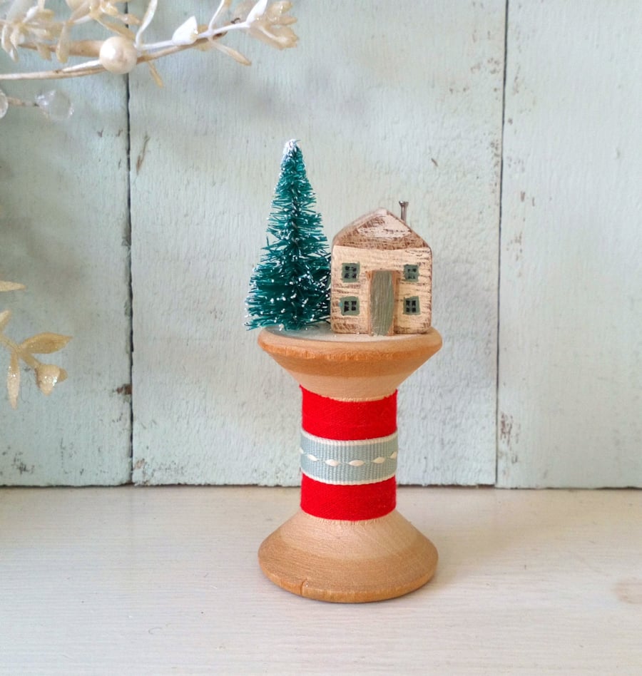 Little wooden Christmas house on a vintage bobbin