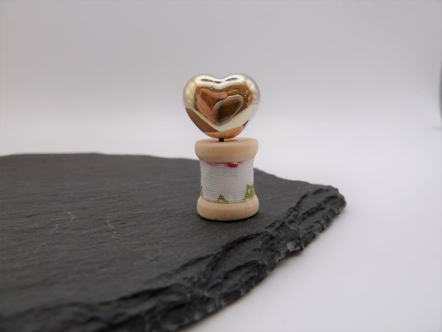 small heart of gold on wooden bobbin
