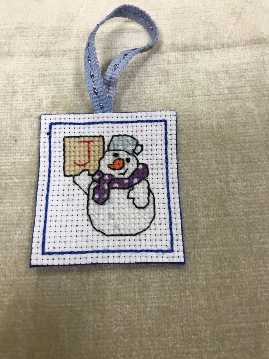 Cross stitched snowman holding a letter J. Cute Christmas tree decoration snowma