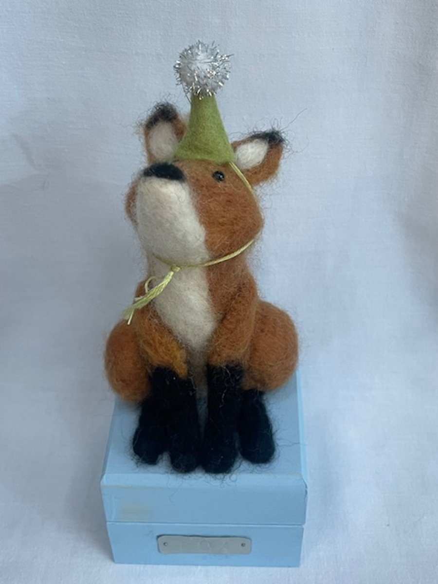 Handcrafted needle felted fox with removable party hat on a wooden box