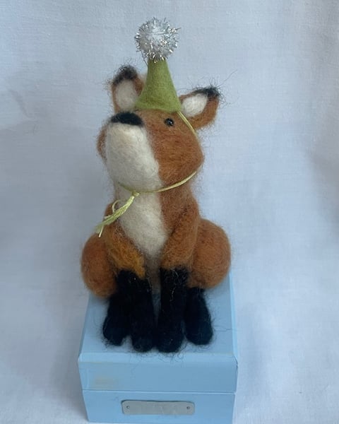 Handcrafted needle felted fox with removable party hat on a wooden box