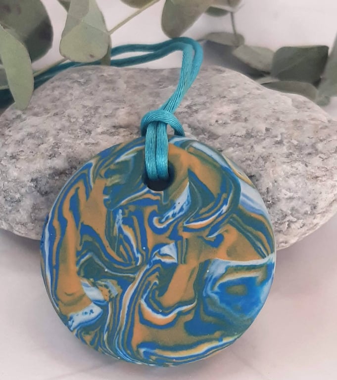 Round pendant in a turquoise, yellow and white polymer clay mix