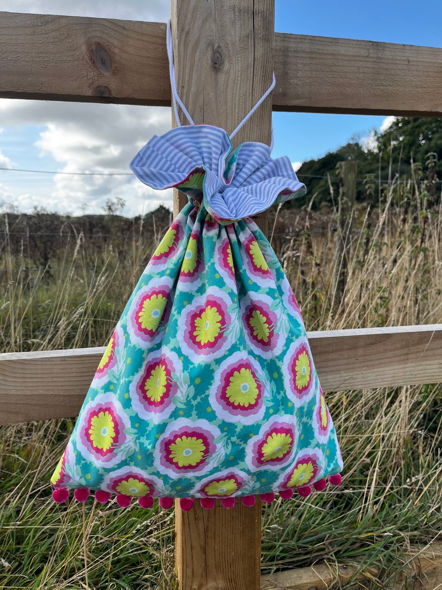 Bright floral drawstring bag with pompoms and reclaimed stripy cotton lining