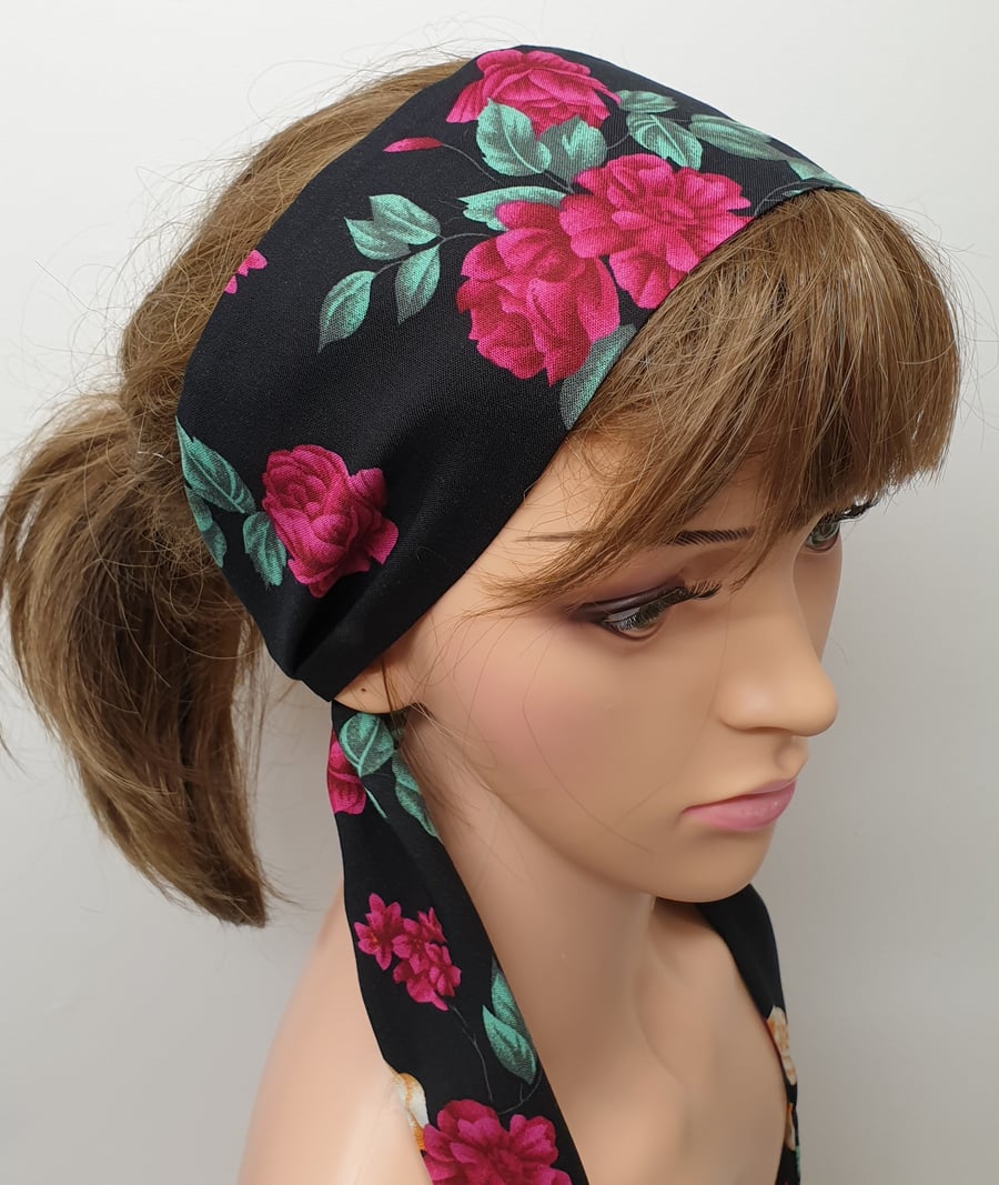 Women tie back black floral head scarf.