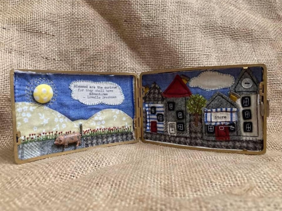 Hand embroidered appliqué picture with lead pig in a vintage cigarette case