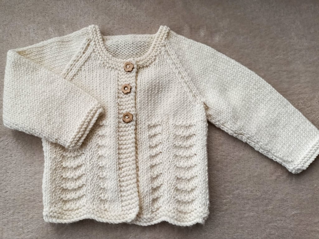 Newborn baby girls cardigan hand-knitted in a soft smooth cream baby yarn with a