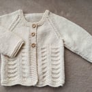 Newborn baby girls cardigan hand-knitted in a soft smooth cream baby yarn with a