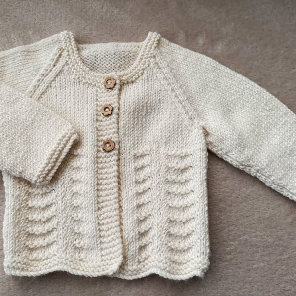 Newborn baby girls cardigan hand-knitted in a soft smooth cream baby yarn with a