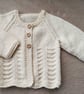 Newborn baby girls cardigan hand-knitted in a soft smooth cream baby yarn with a