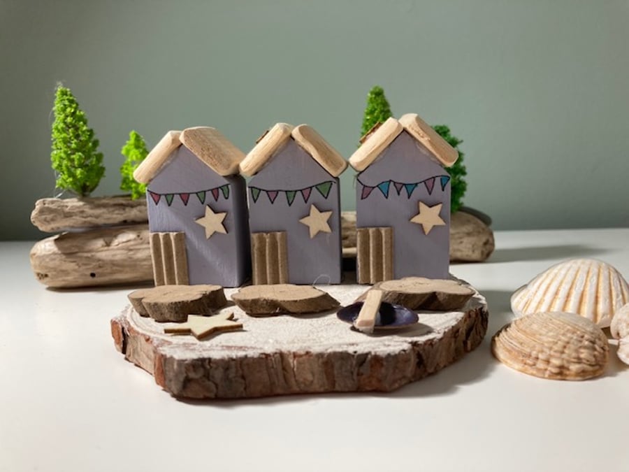 Trio of tiny wooden beach huts set on a wood slice