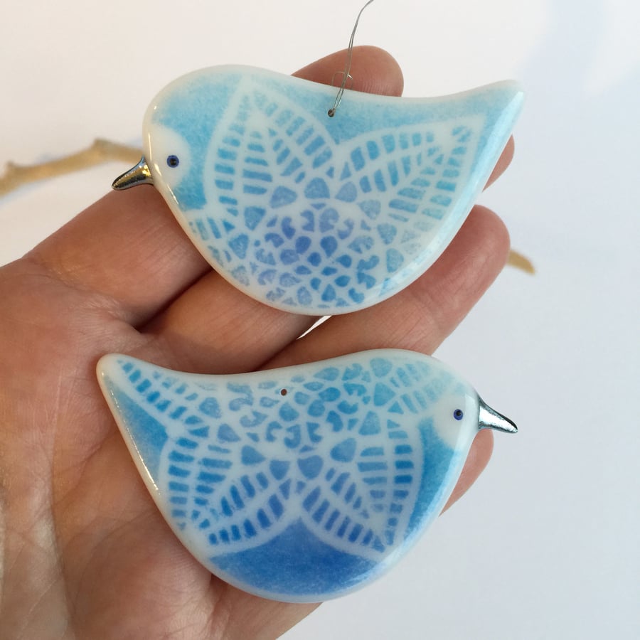 A pair of turqoise birds facing each other. 