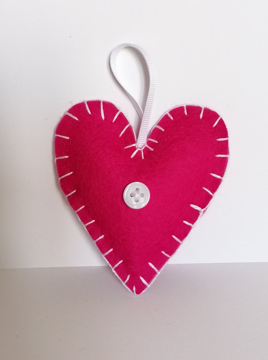 Handmade pink felt heart with white stitching, ribbon and button 