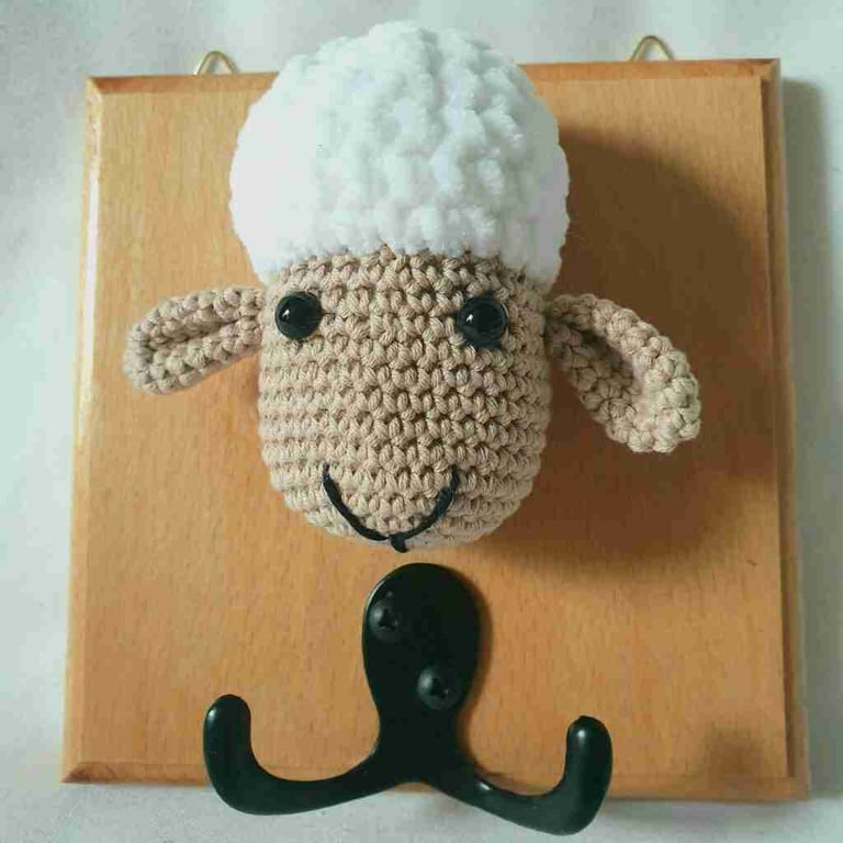 Crocheted sheep head on wooden board with hooks