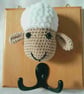 Crocheted sheep head on wooden board with hooks