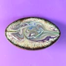 Narrow oval brooch - purple, mauve, grey-green, dark yellow scrollwork on white 