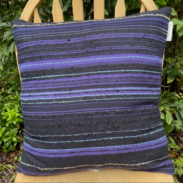 Cushion , handwoven in subtly striped textures in navy blue,  purple and black
