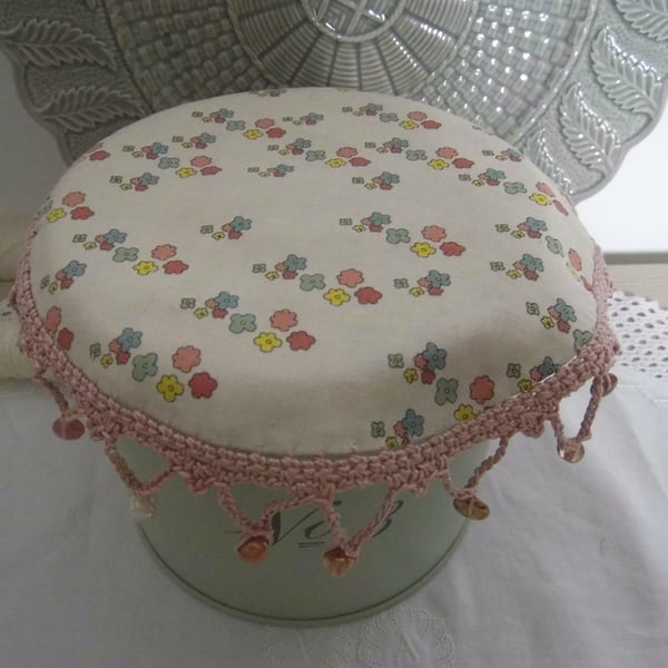 Flower print fabric jug cover, with crochet edging and glass beads.
