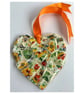 A heart shaped mosaic pendant with a wild flowers theme in orange and green.