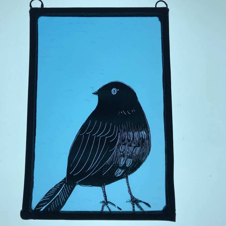 Hand-painted bird on transparent blue stained glass panel.