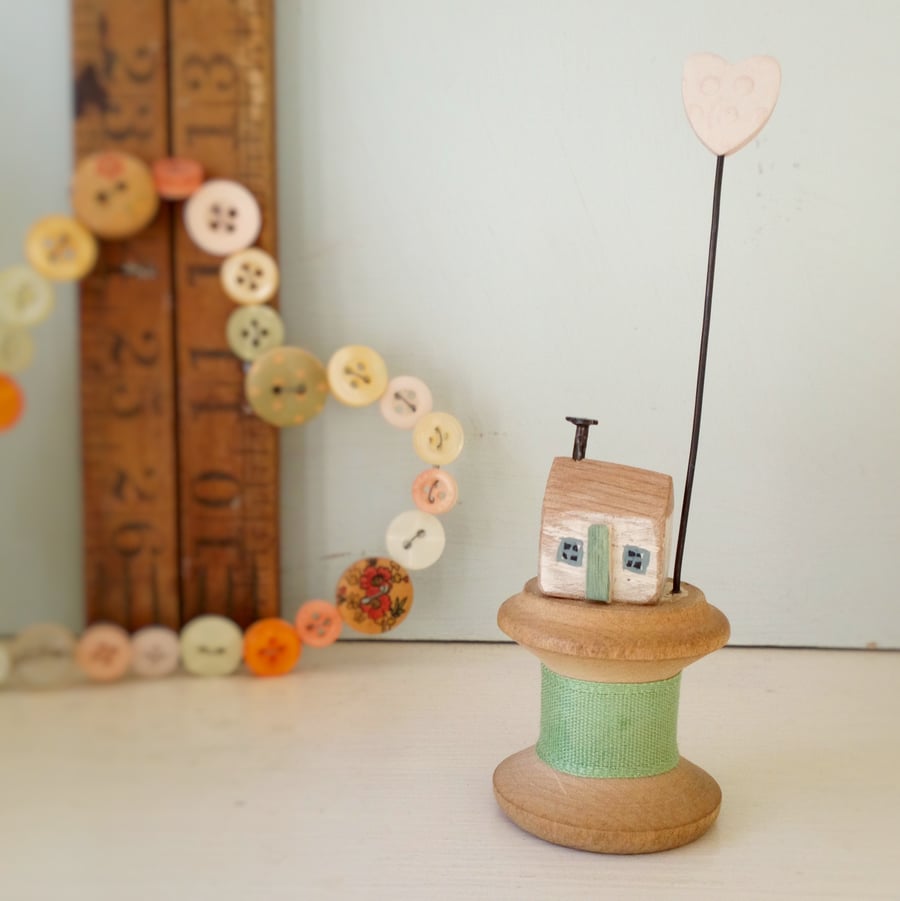 Tiny oak house with clay heart on vintage wooden bobbin