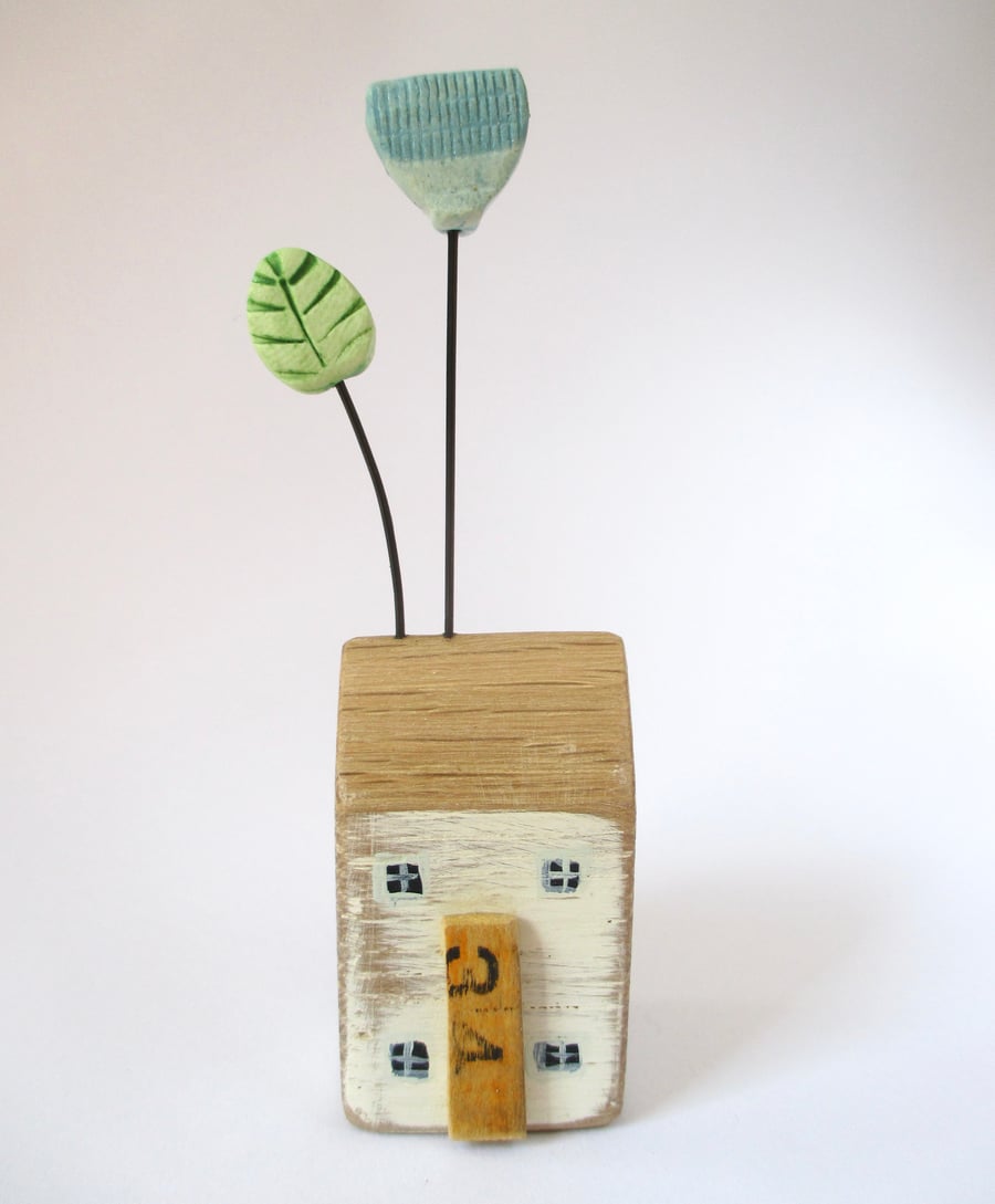 Little wooden house with a clay flower and leaf