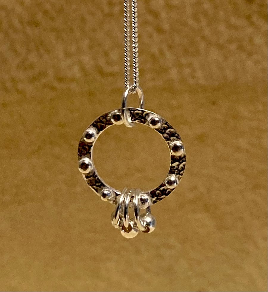 Circular silver necklace with tiny silver studs and 3 rings 