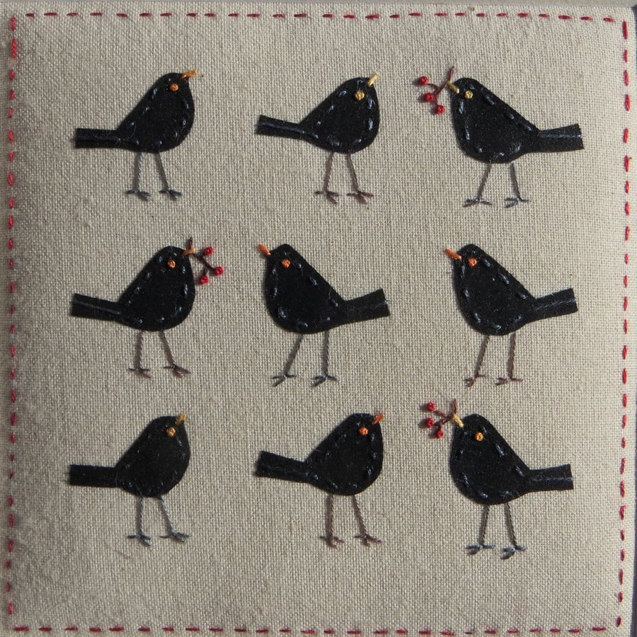 Small framed hand-stitched textile of blackbirds with bright red berries