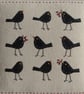Small framed hand-stitched textile of blackbirds with bright red berries