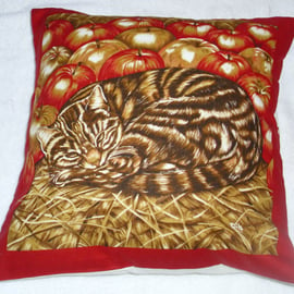 A brown tabby cat curled up in the straw with apples cushion