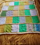 Baby or toddler handmade knitted blanket in a yellow and green theme.