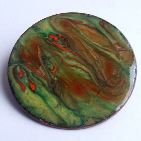 large round enamelled brooch scrolled red-brown and orange on green 