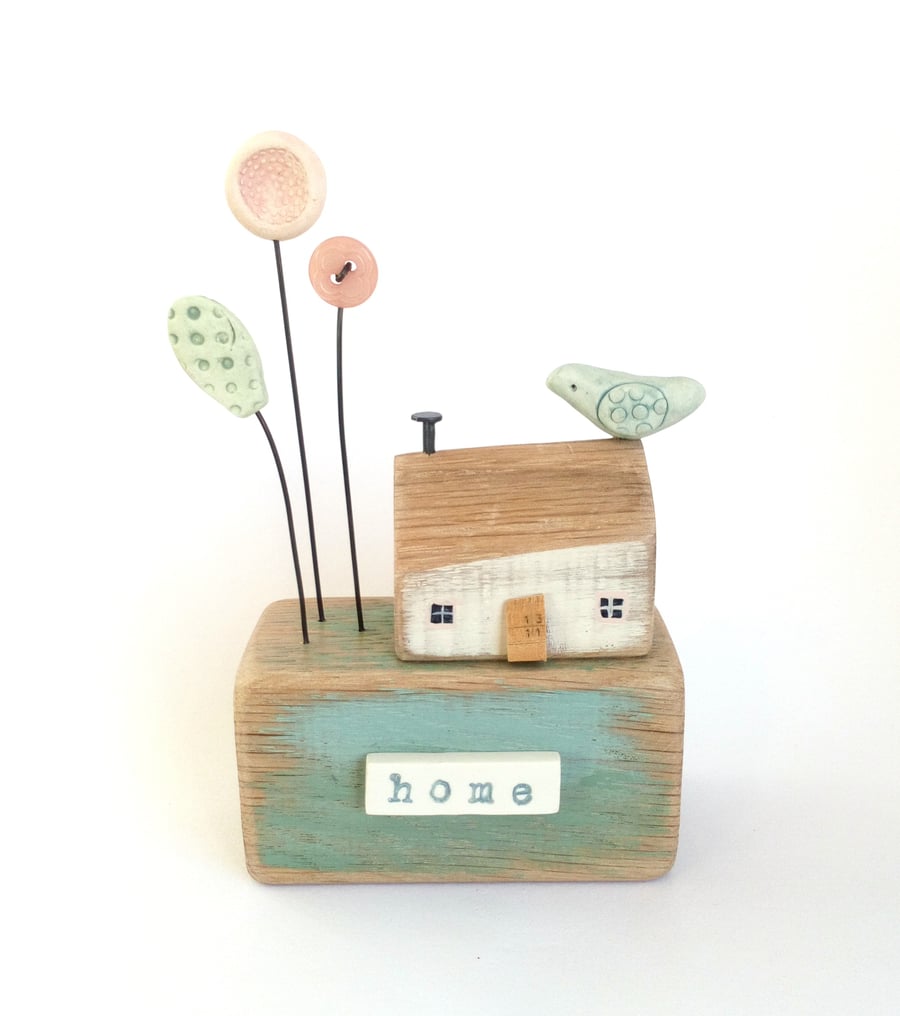 Little wooden house with clay flowers and bird