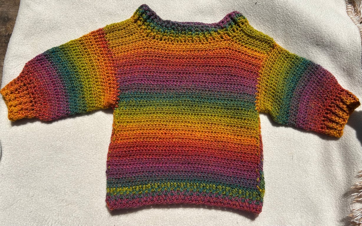 Rainbow jumper for a small child, perfect for festivals and every day wear.