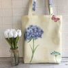 Floral tote bag in pale yellow with a stem of blue flowers and pink butterfly