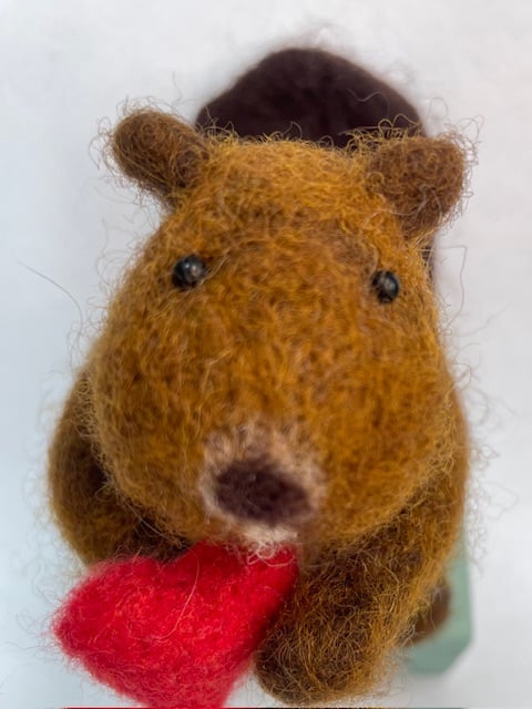 Handcrafted needle felted beaver holding a heart on a wooden box