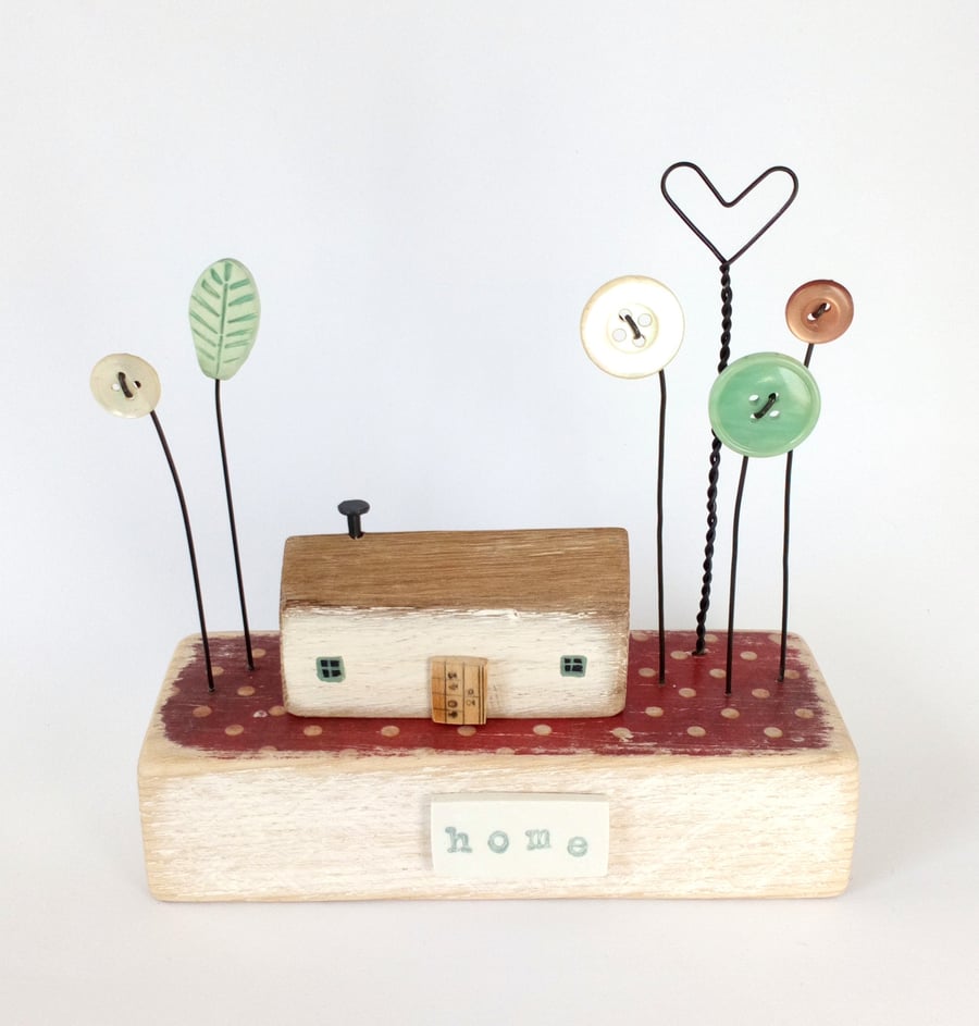 Wooden painted house with button and clay flower garden