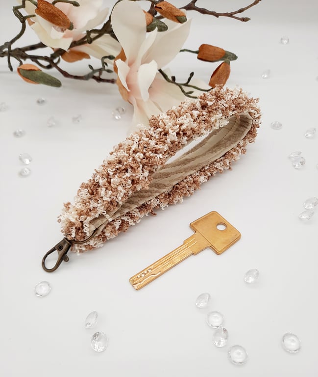 Keyfob wristlet, with a cream and light brown curly trim. 