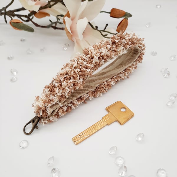 Keyfob wristlet, with a cream and light brown curly trim. 