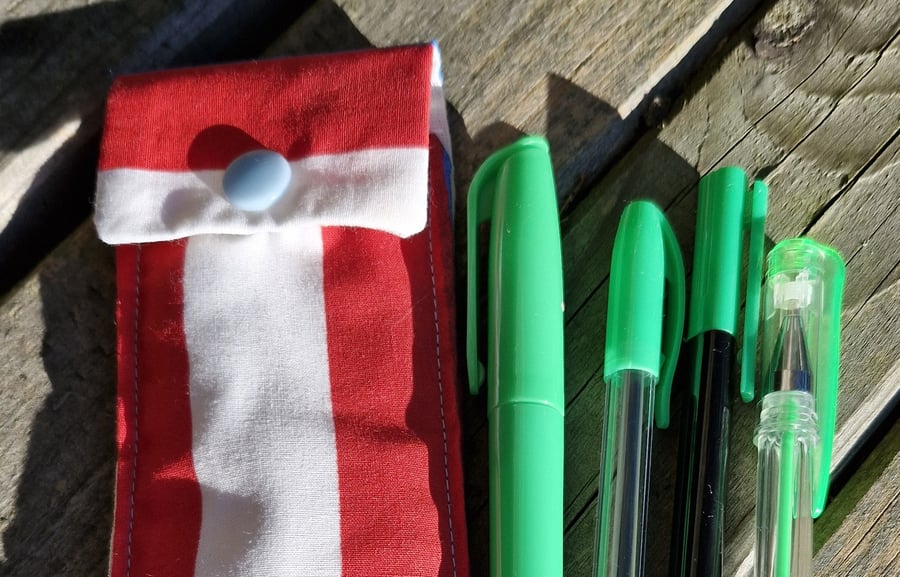 Red white and blue striped  pen case with 4 green pens.