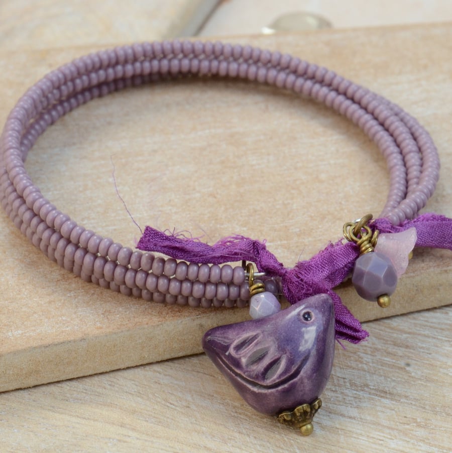 Purple Seed Bead Memory Wire Wrap Bracelet with Ceramic Bird Charm