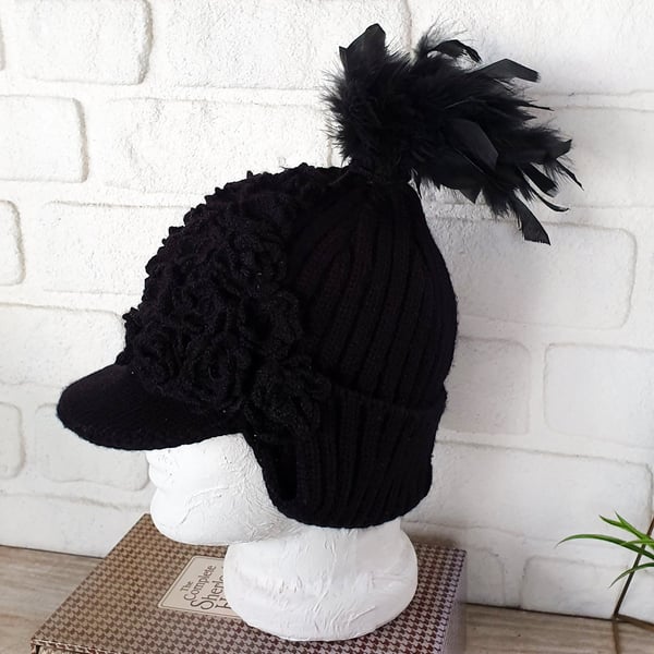 Black helmet style crochet hat with black crochet flowers and feathered tail