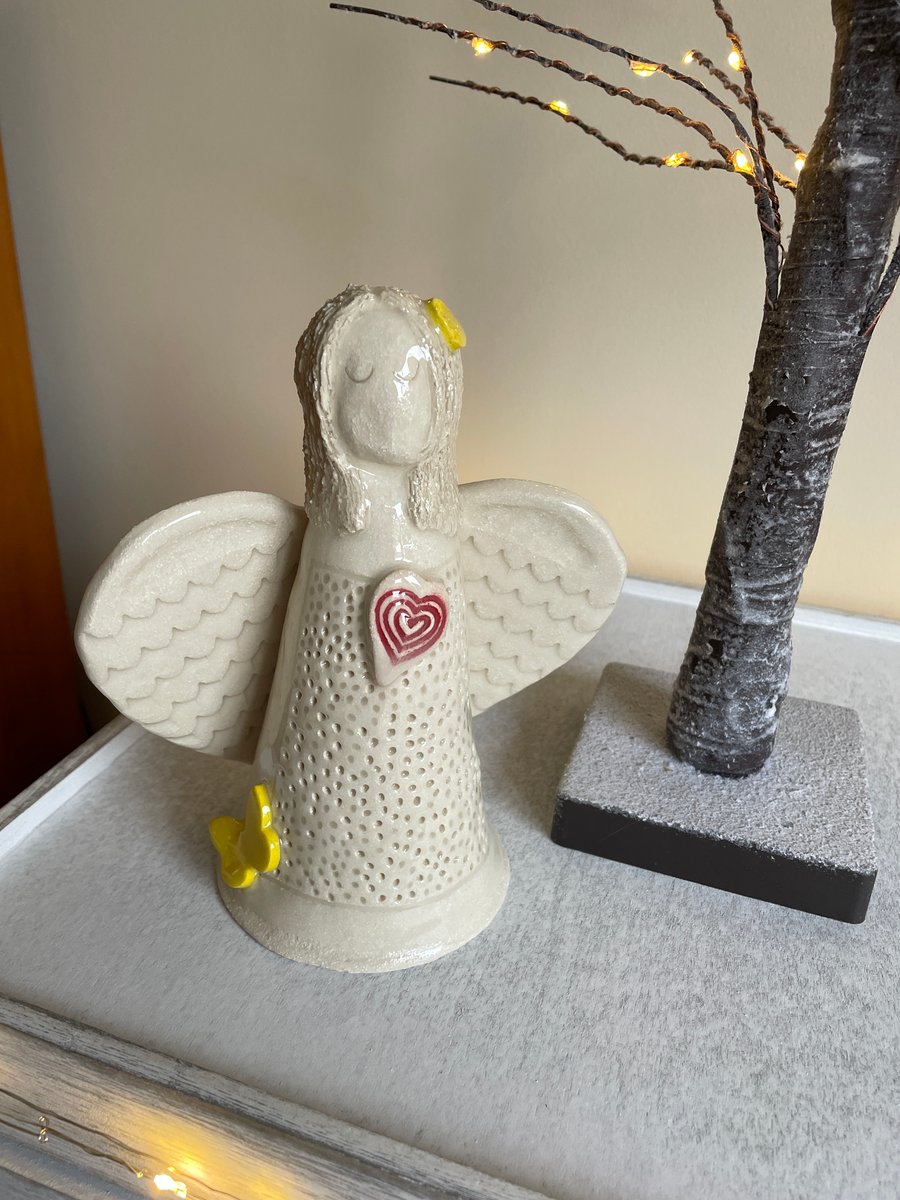 Ceramic angel sculpture with red heart, yellow butterfly and flower