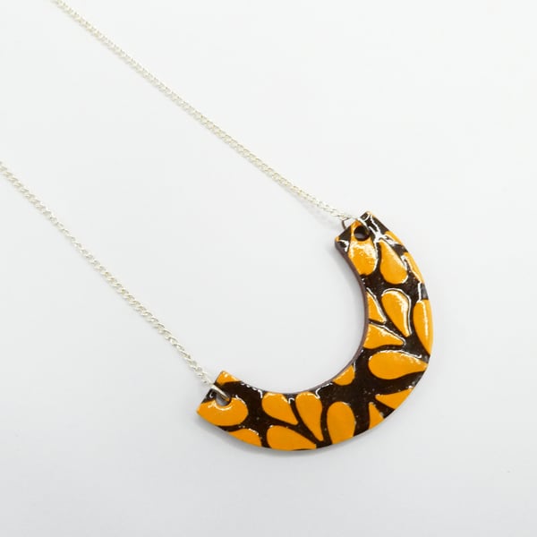 Ceramic arc pendant in orange and brown on a curb chain necklace