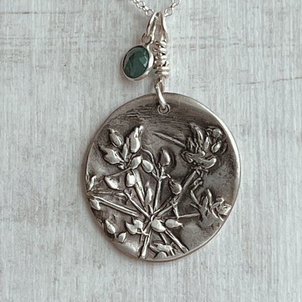 Botanical silver pendant with emerald charm.